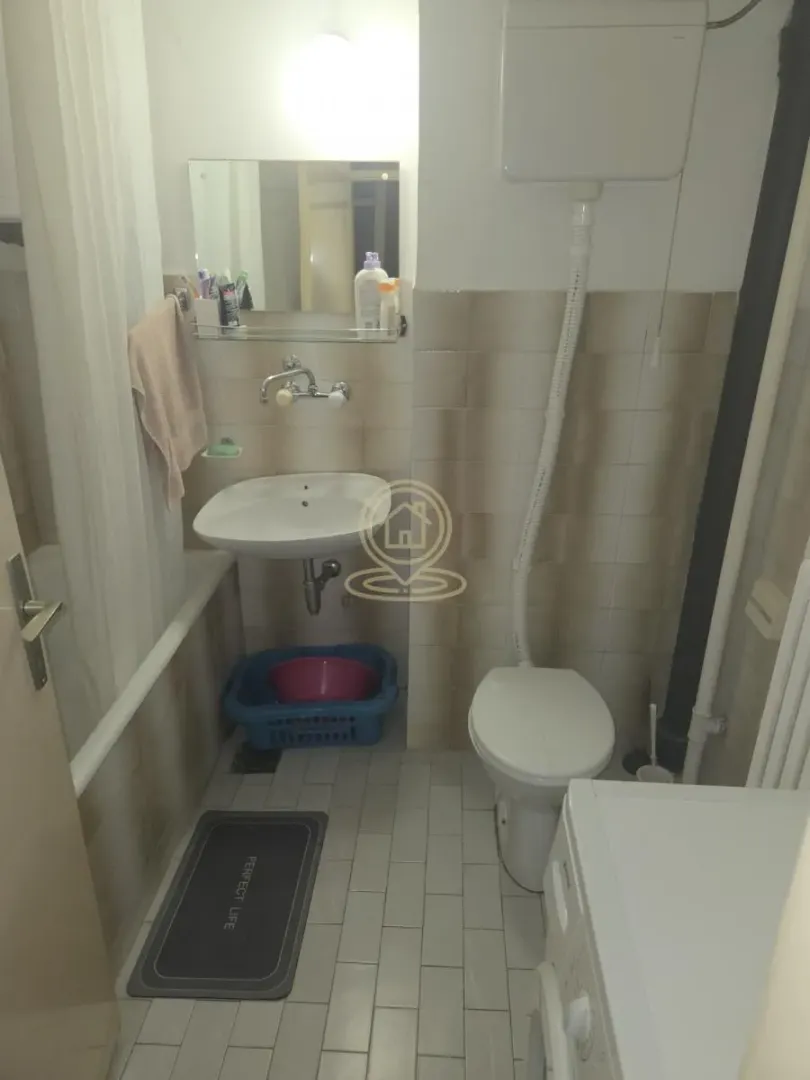 Manje kupatilo sa kadom, umivaonikom, wc šoljom i veš mašinom.