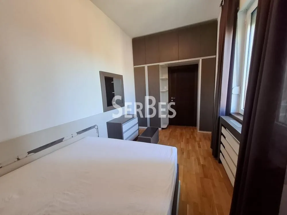 Nameštena spavaća soba sa bračnim krevetom, garderoberom i prozorom.