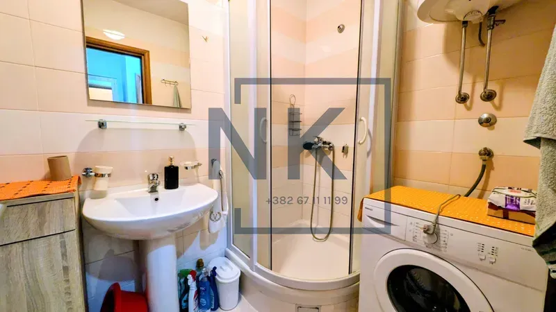 Bathroom with a shower cabin, washbasin, and washing machine.