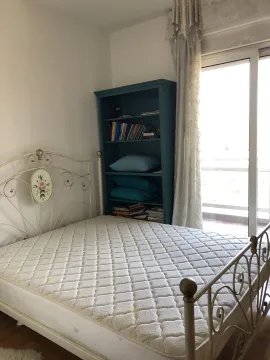 Bedroom with a metal bed and a bookshelf next to balcony doors. - image 20