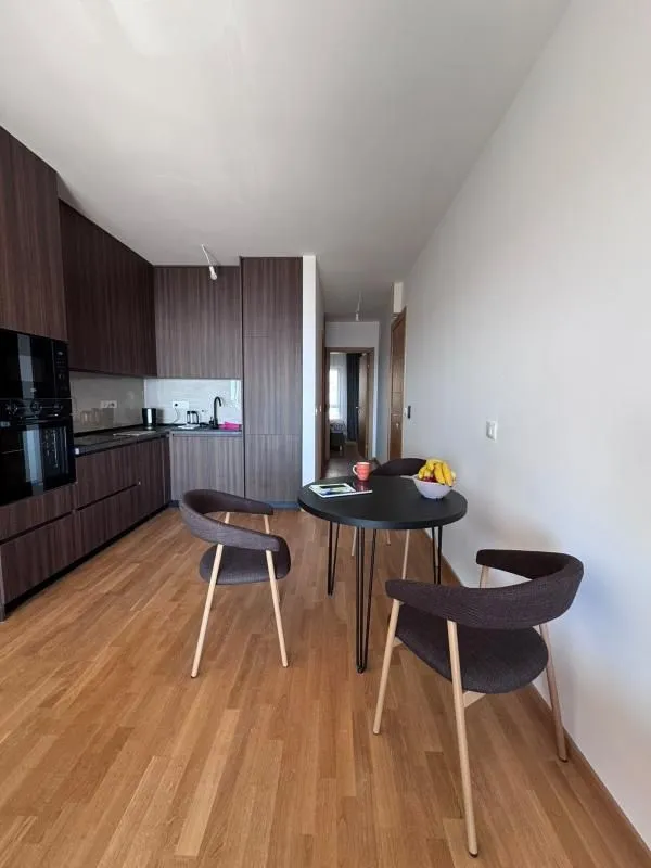 Modern kitchen with dark cabinetry and a dining table with chairs.