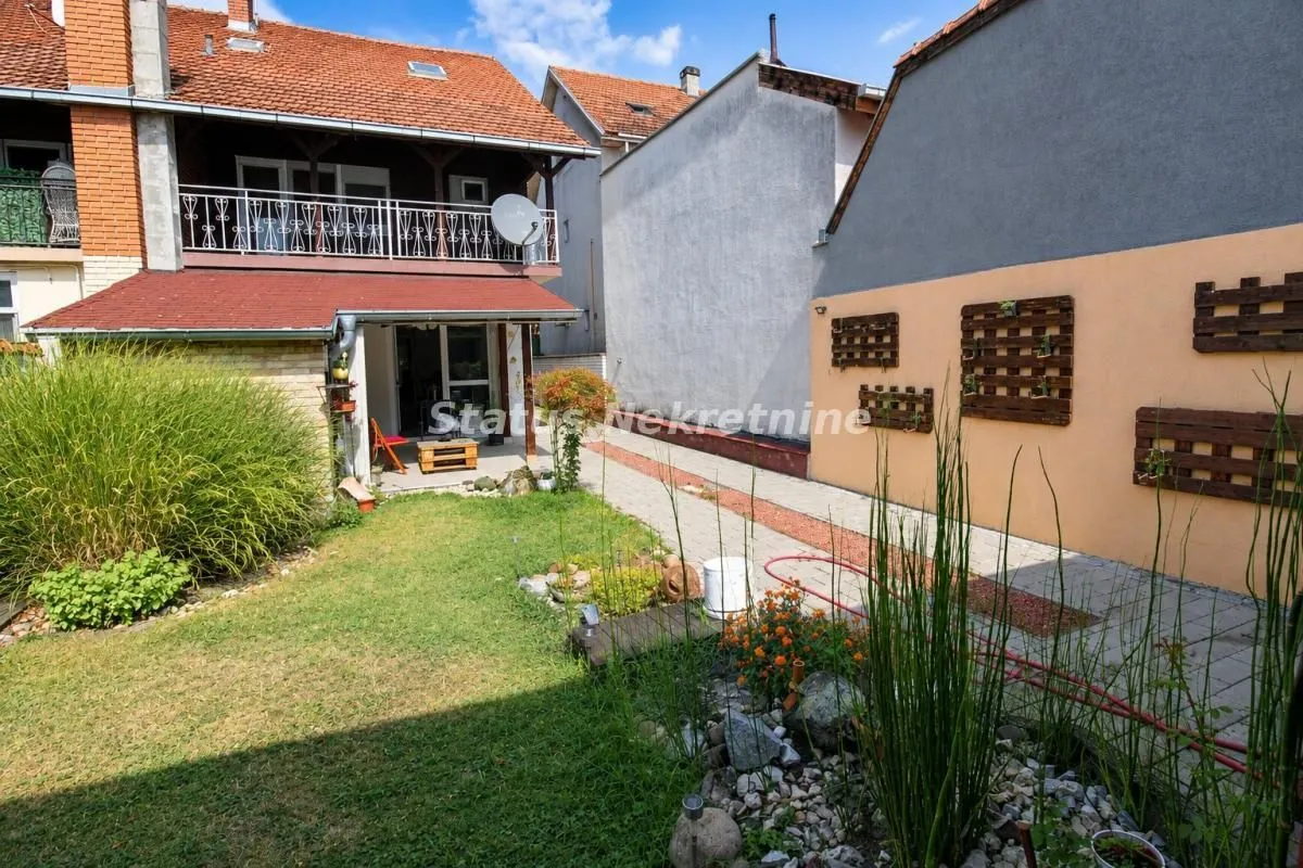 Pogled na dvorište i zadnju stranu kuće sa balkonom.