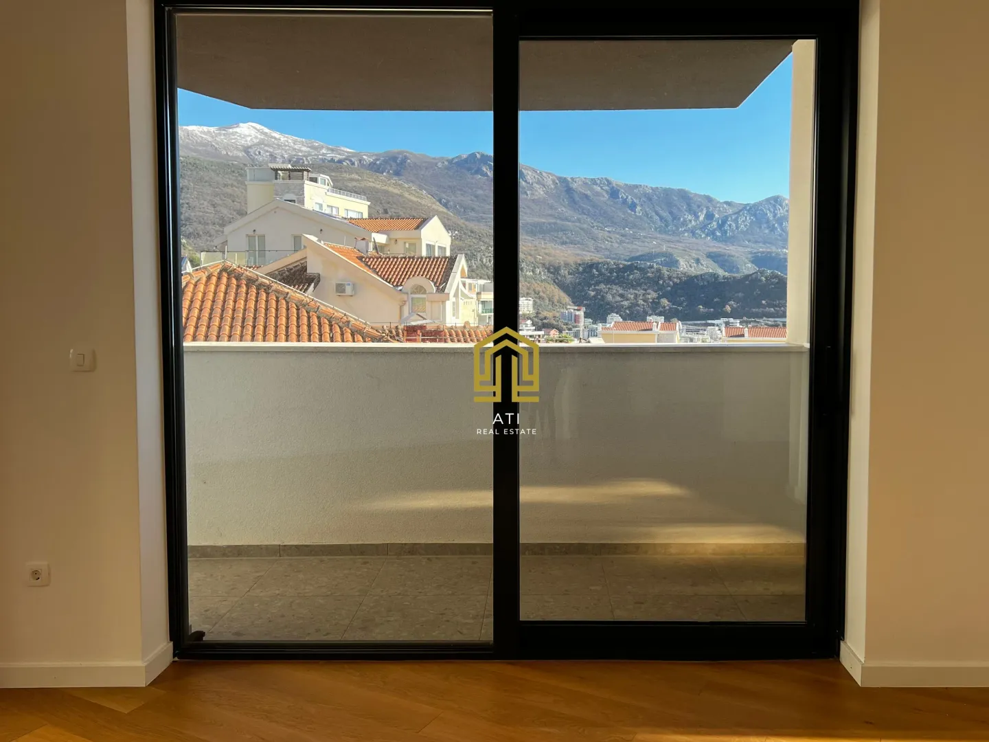 Pogled kroz veliku staklenu balkonsku vrata na planine i grad.