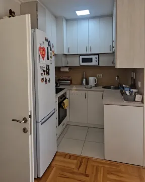 Manja kuhinja sa bijelim elementima, frižiderom i ugradnom rernom. - image 2