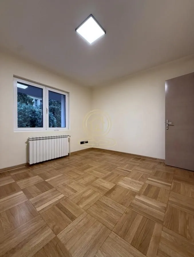 Prazna soba sa parketom na podu i prozorom.
