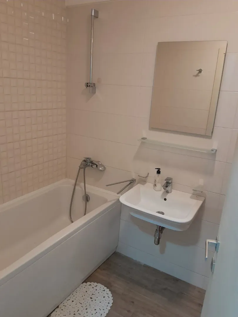 Bathroom equipped with a bathtub, washbasin, and mirror.