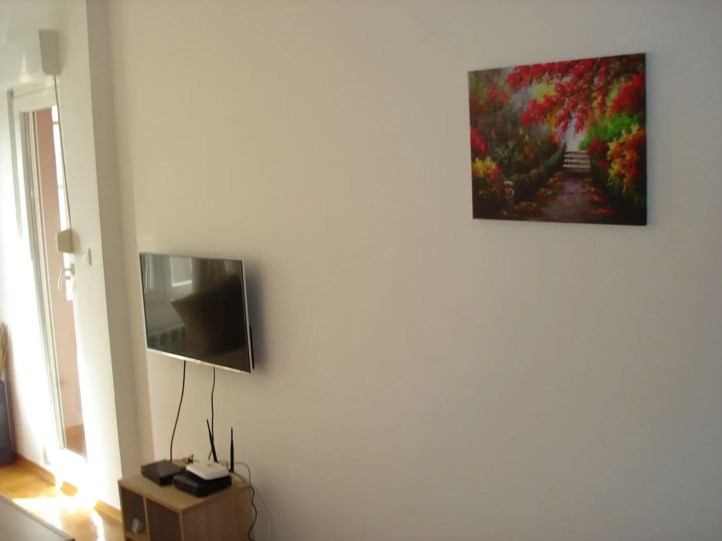 White wall with a television and an art painting.