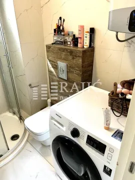 Smaller bathroom with a shower cabin, toilet, and washing machine. - image 2