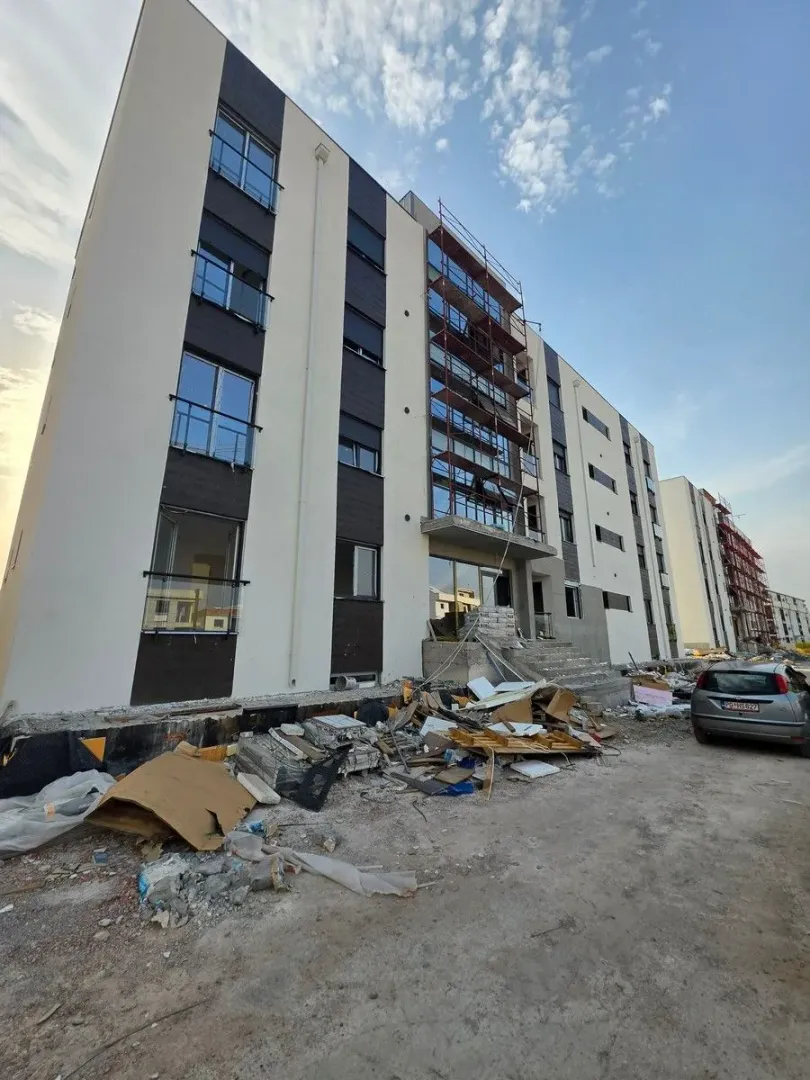 Spoljašnji izgled zgrade u izgradnji sa građevinskim otpadom ispred ulaza.
