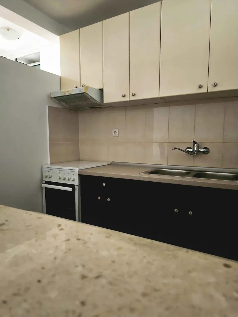 Small kitchen with lower black cabinets and upper beige cabinets.