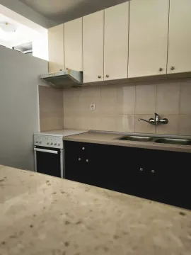 Small kitchen with lower black cabinets and upper beige cabinets. - image 8