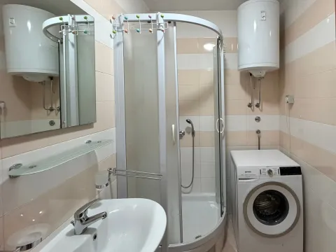Bathroom equipped with a shower cabin, washbasin, water heater, and washing machine. - image 8