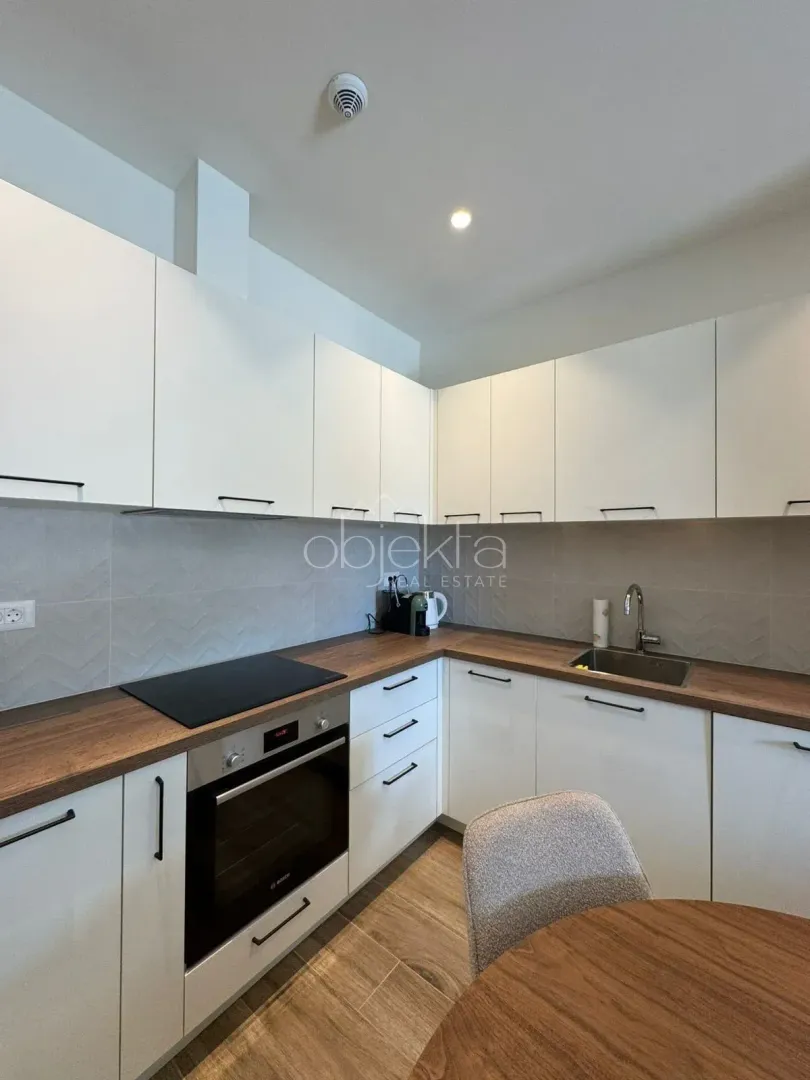 Modern kitchen with white cabinets and a wooden countertop.
