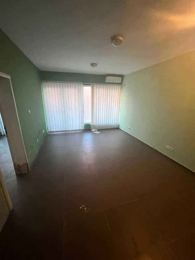 Empty room with dark floor tiles and window blinds.
