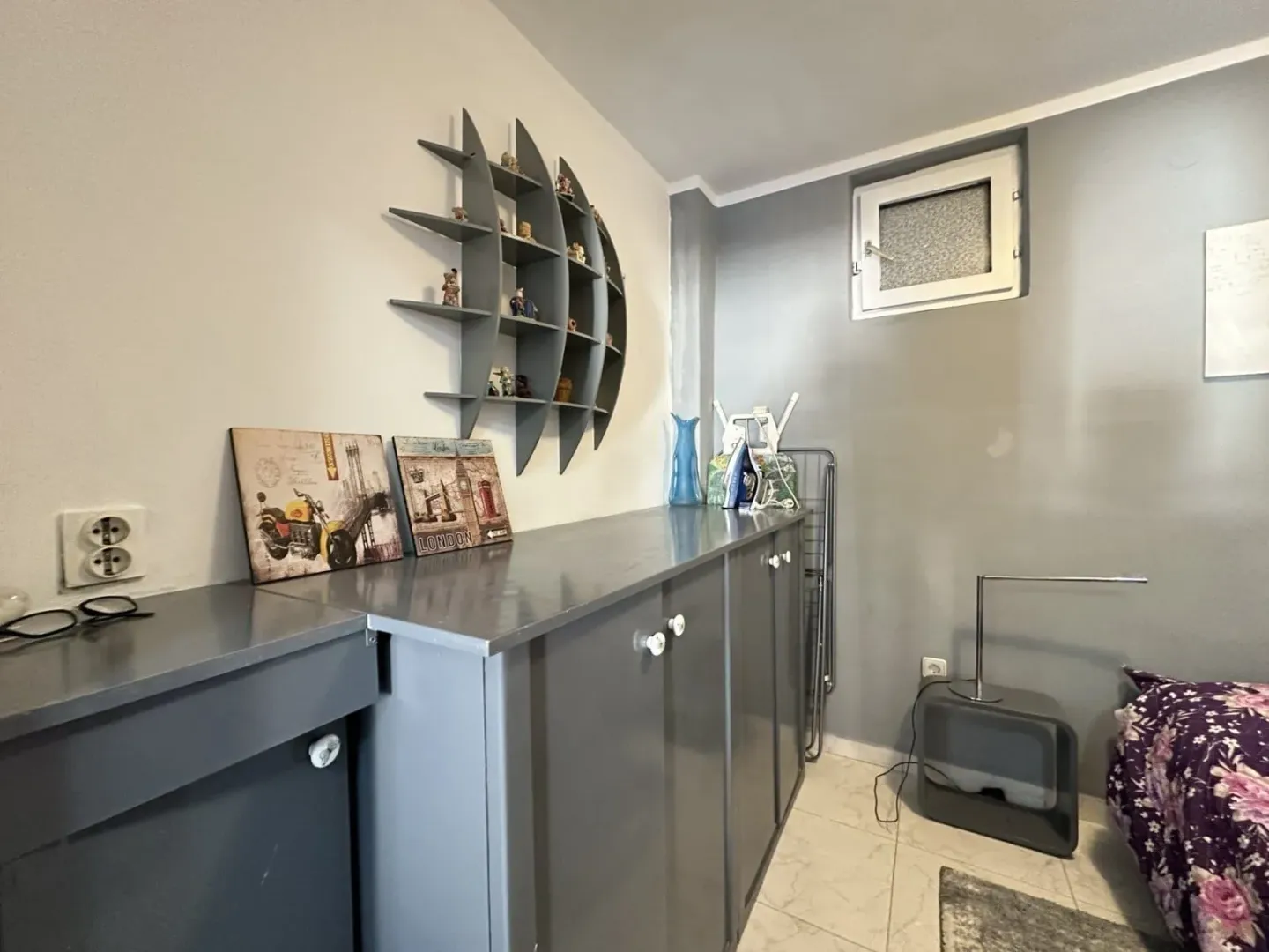 Small bedroom with grey furniture and a decorative wall shelf.
