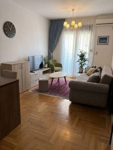 Namještena dnevna soba sa garniturom, televizorom i trpezarijskim dijelom.