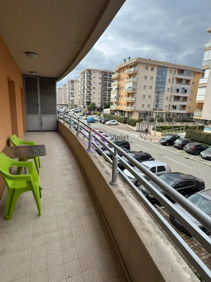 Covered balcony with outdoor seating and a view of the street and buildings.