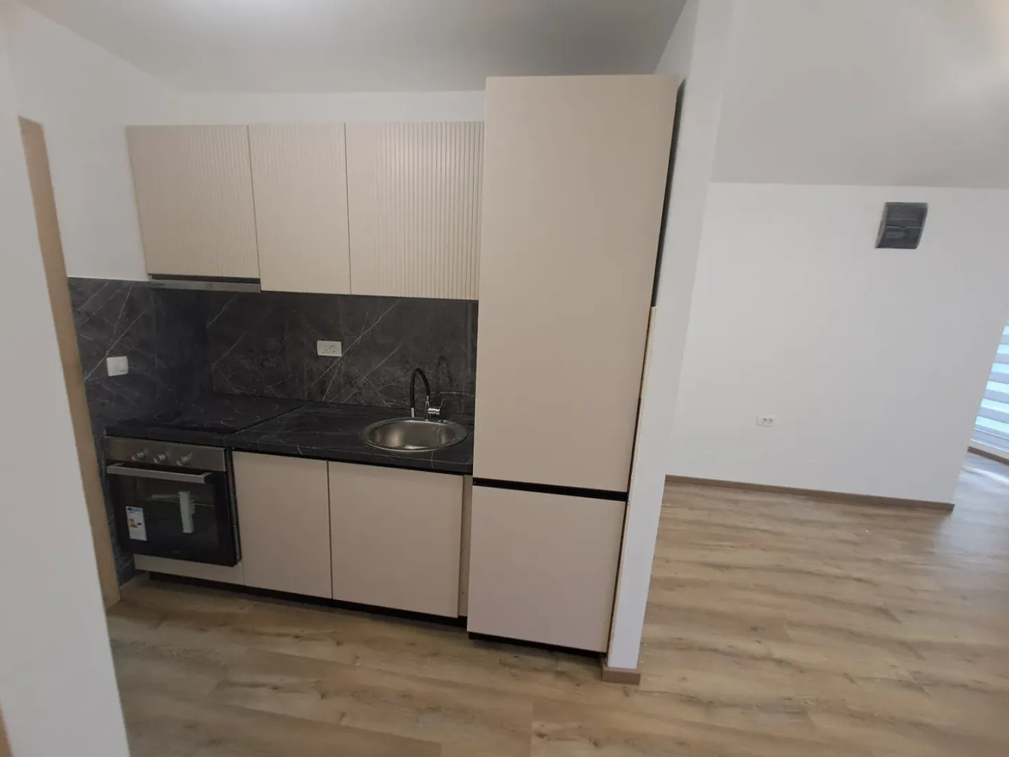 Small kitchen within the living area with built-in cabinetry and appliances.