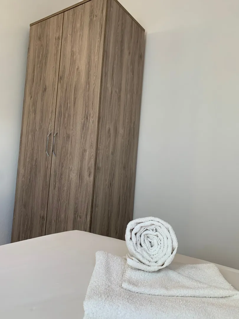 Bedroom with a wardrobe and towels on the bed.