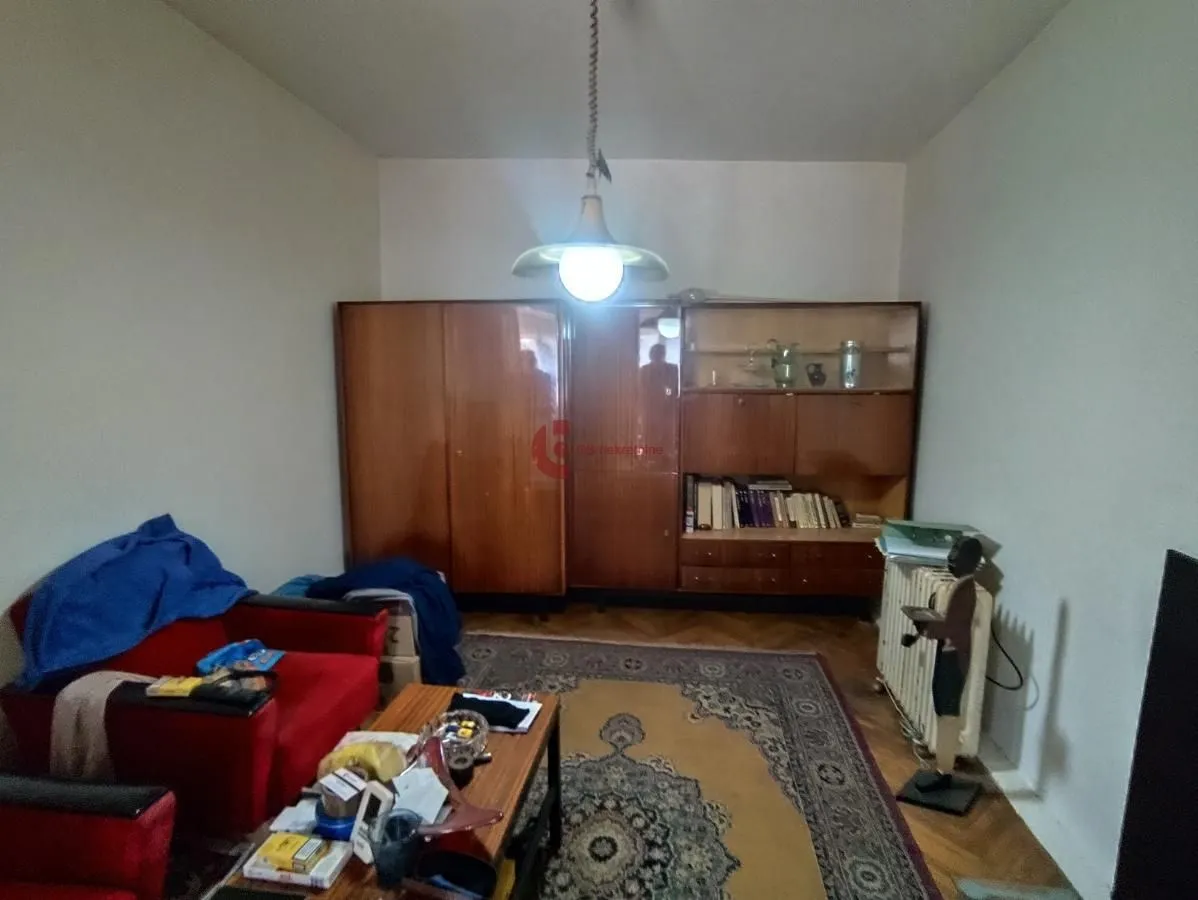 Dnevna soba sa garniturom, velikim drvenim ormarom i tepihom na podu.