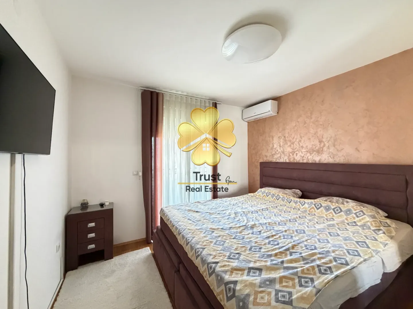 Furnished bedroom with a double bed, TV, and air conditioning.