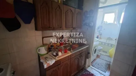 Starija kuhinja sa drvenim elementima i neredom na radnoj površini. - image 5