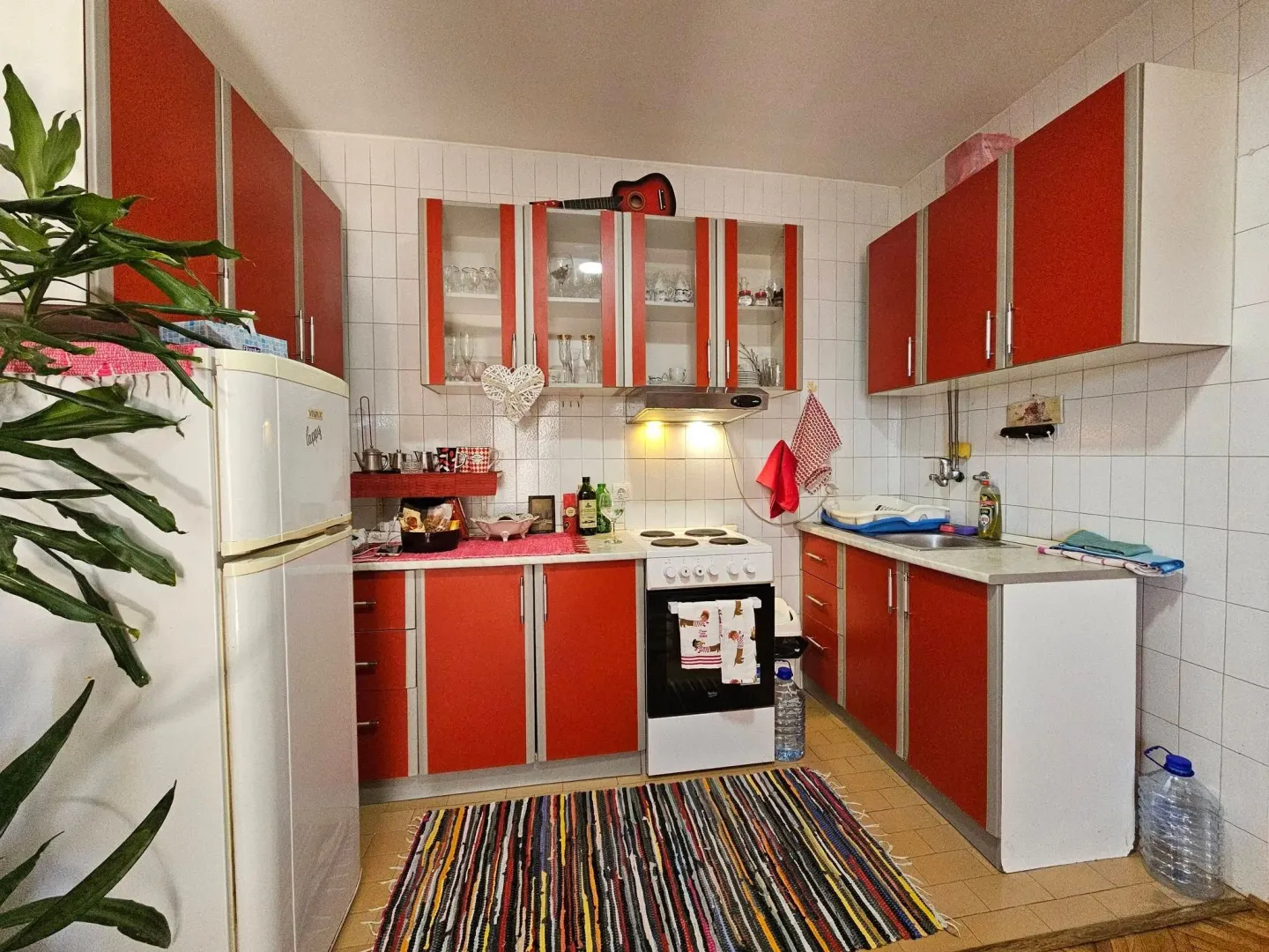 Small kitchen with red cabinets and white appliances.