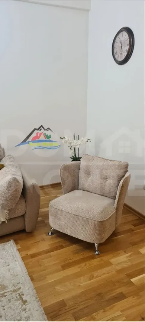 Dio dnevnog boravka sa foteljom i ukrasnim satom na zidu.