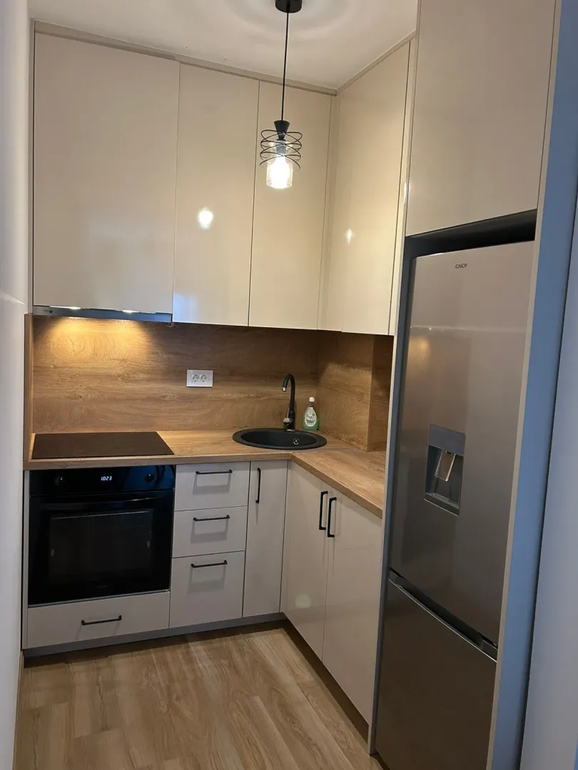 Modern and compact kitchen with built-in appliances and a refrigerator.
