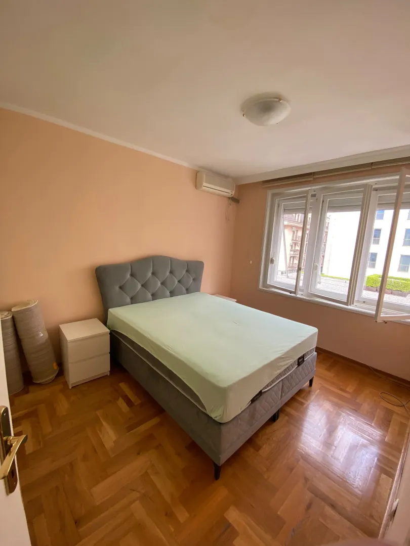 Spavaća soba sa bračnim krevetom, noćnim stočićima i prozorom.