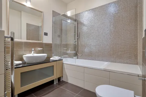 Modernly equipped bathroom with a bathtub, shower enclosure, washbasin, and mirror. - image 5