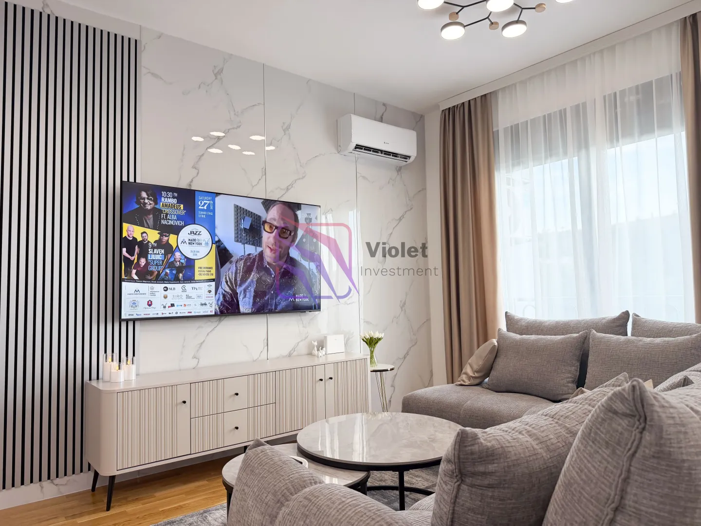 Moderna dnevna soba sa ugaonom garniturom, televizorom i mermernom pozadinom.