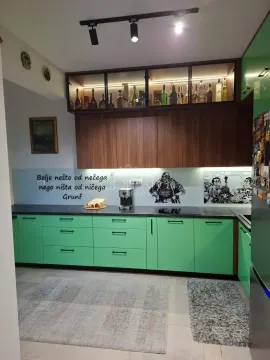 Moderna kuhinja sa zelenim elementima, drvenim gornjim ormarićima i osvijetljenom vitrinom. - image 6