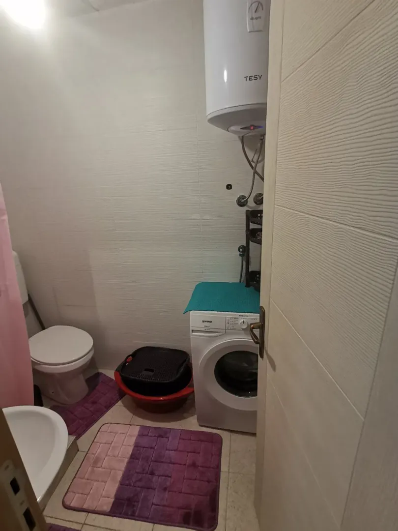 Small bathroom with a washing machine and water heater.