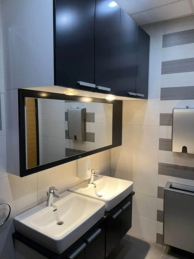 Modern bathroom with two sinks, a large mirror, and black cabinets.