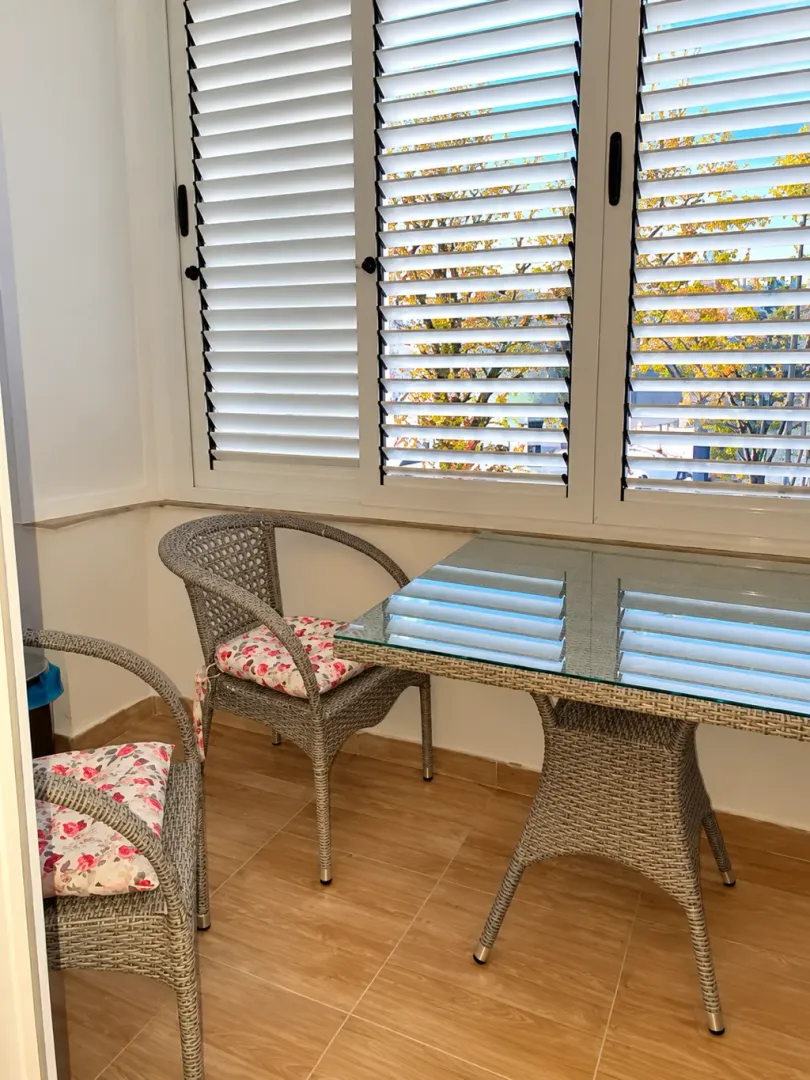 Enclosed balcony with wicker furniture and an outdoor view.