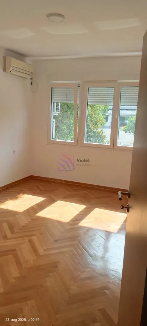 Empty room with parquet flooring and air conditioning.