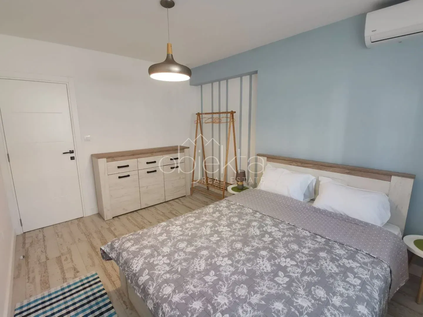 Furnished bedroom with a double bed, chest of drawers, and air conditioning.