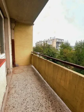Natkriveni balkon sa pogledom na okolne zgrade i zelenilo. - image 12