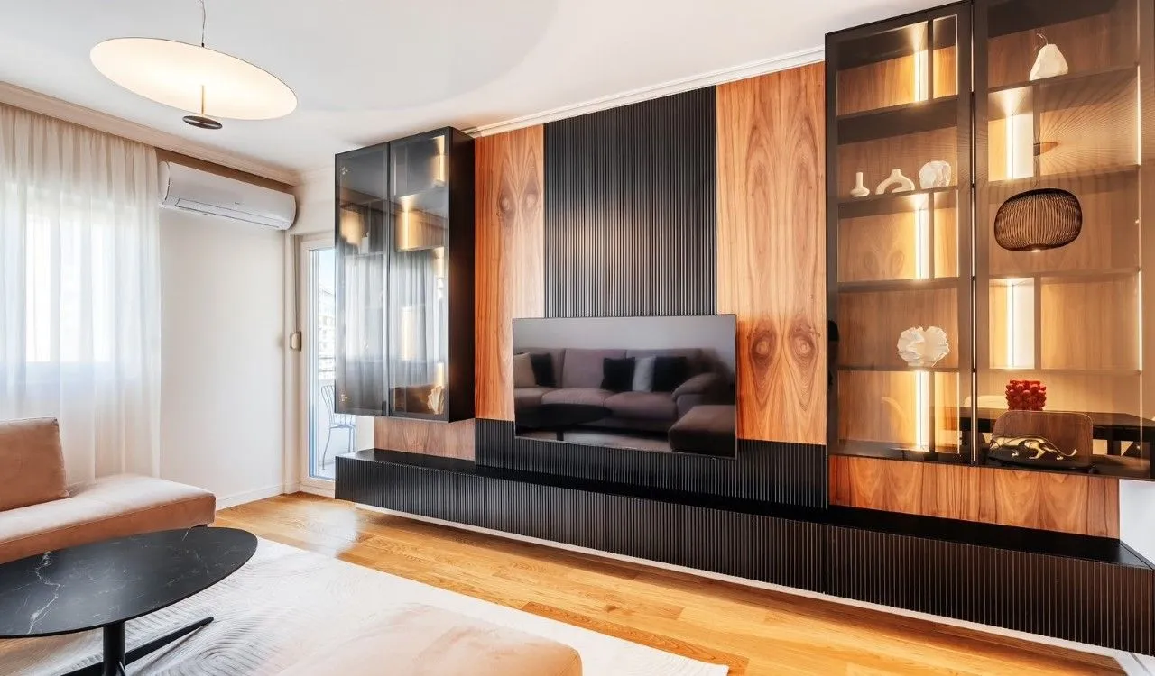 Modern living room with built-in cabinets, television, and wooden wall panels.