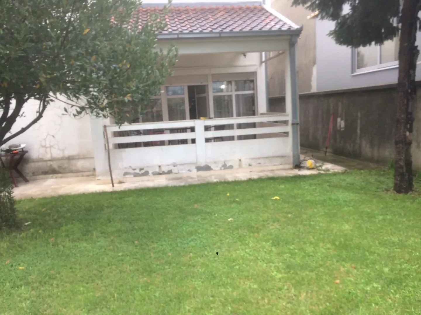 Yard and house facade with a covered terrace.