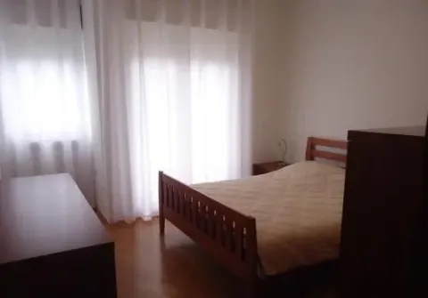 Simply furnished bedroom with a wooden bed and white curtains. - image 6