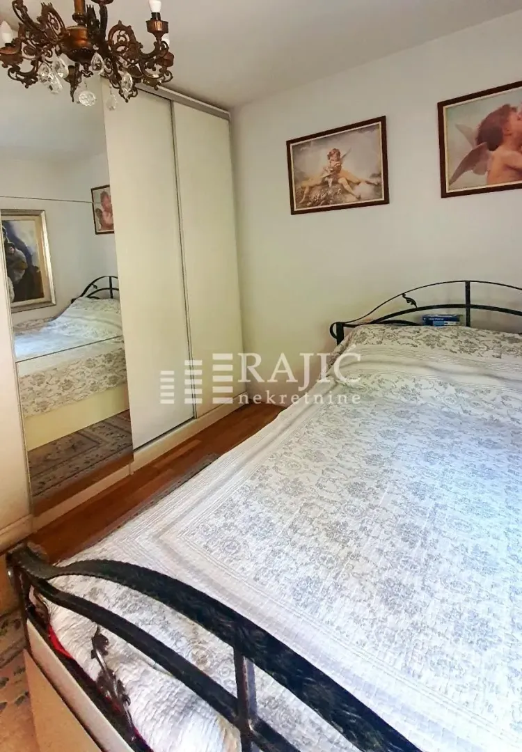A bedroom with a double bed, mirrored wardrobe, and framed artwork on the wall.