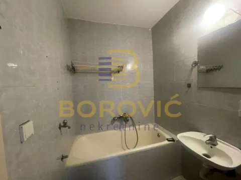 Kupatilo sa kadom, umivaonikom i ogledalom obloženo sivim pločicama. - image 9