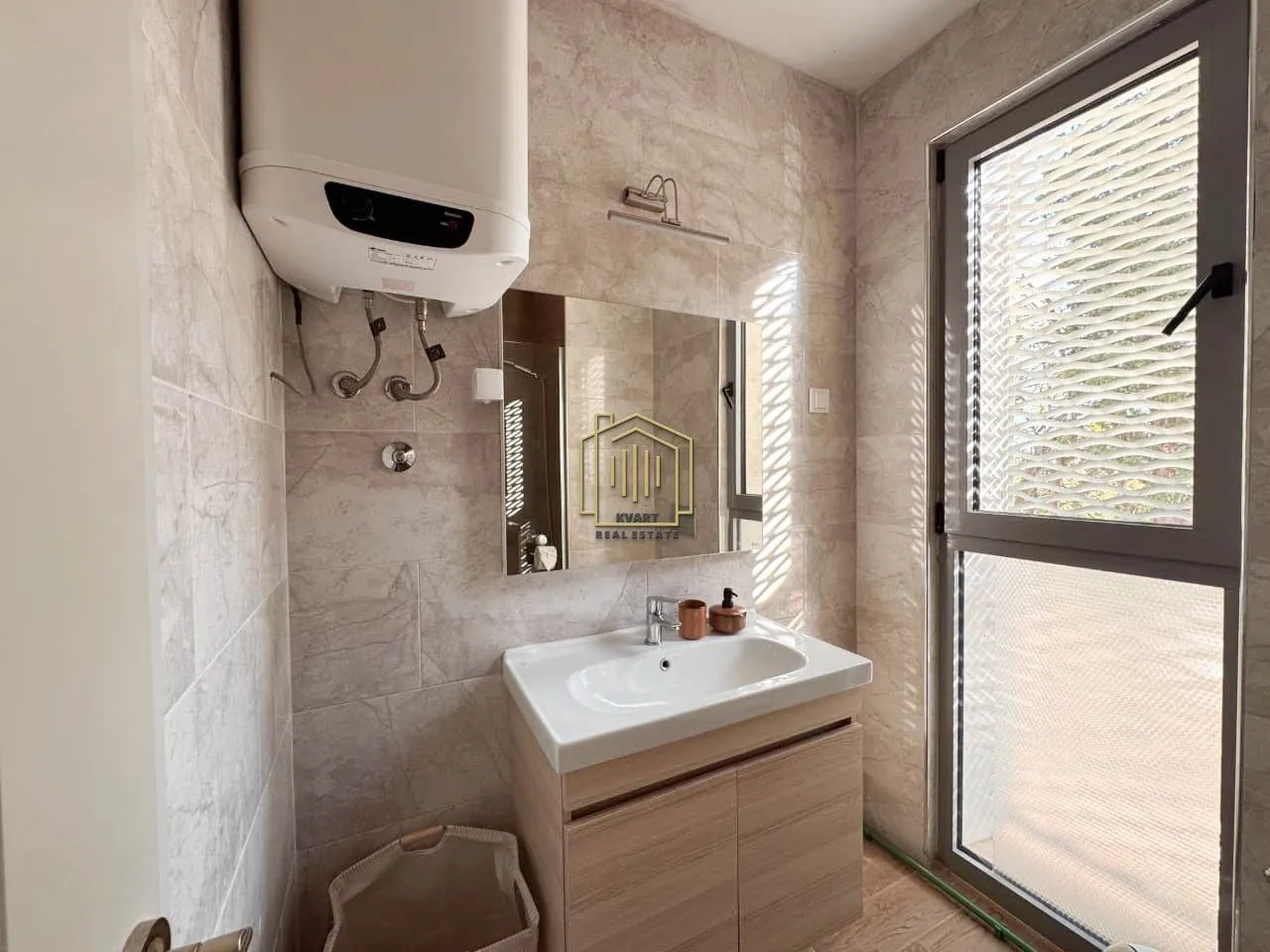 Tiled bathroom featuring a vanity sink, cabinet, and water heater.