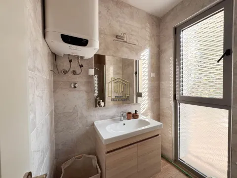 Tiled bathroom featuring a vanity sink, cabinet, and water heater. - image 9