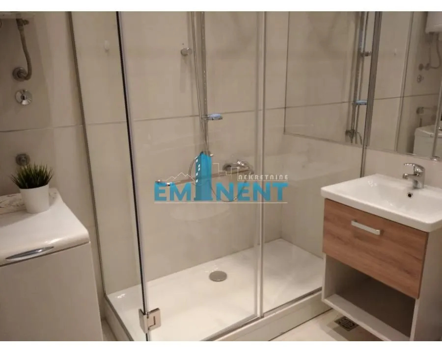 Bathroom equipped with a shower cabin, washbasin, and washing machine.