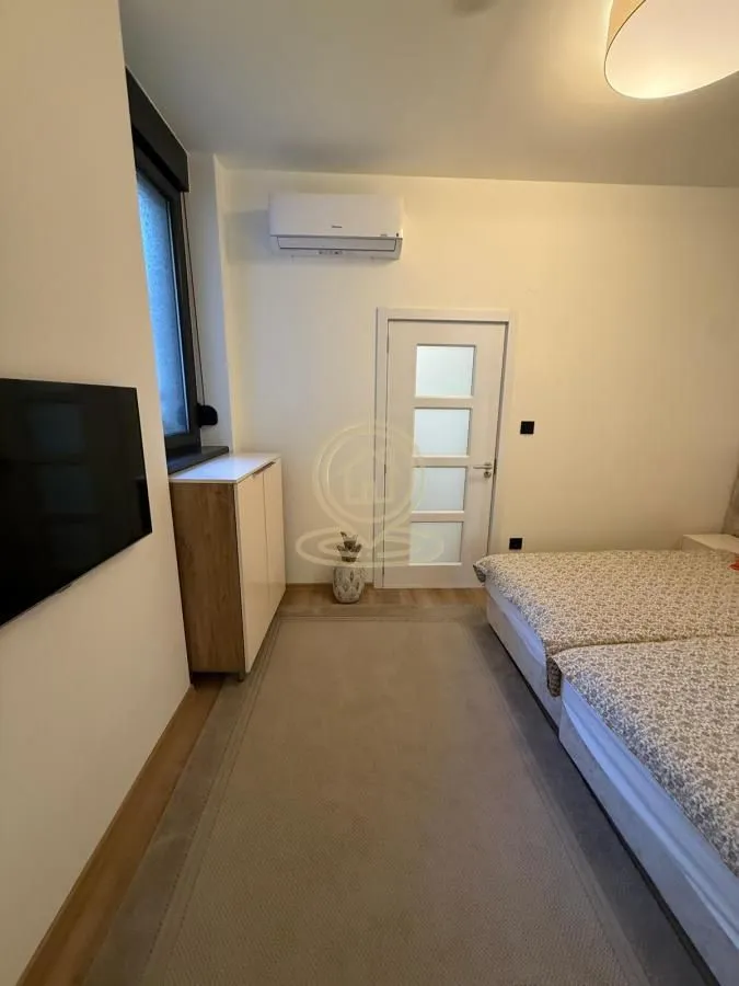Pogled na spavaću sobu sa krevetom, klima-uređajem i televizorom.
