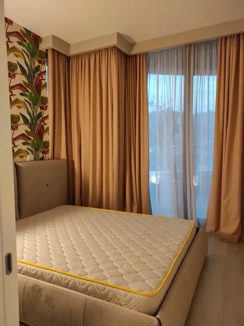 Furnished bedroom with a double bed and curtains.