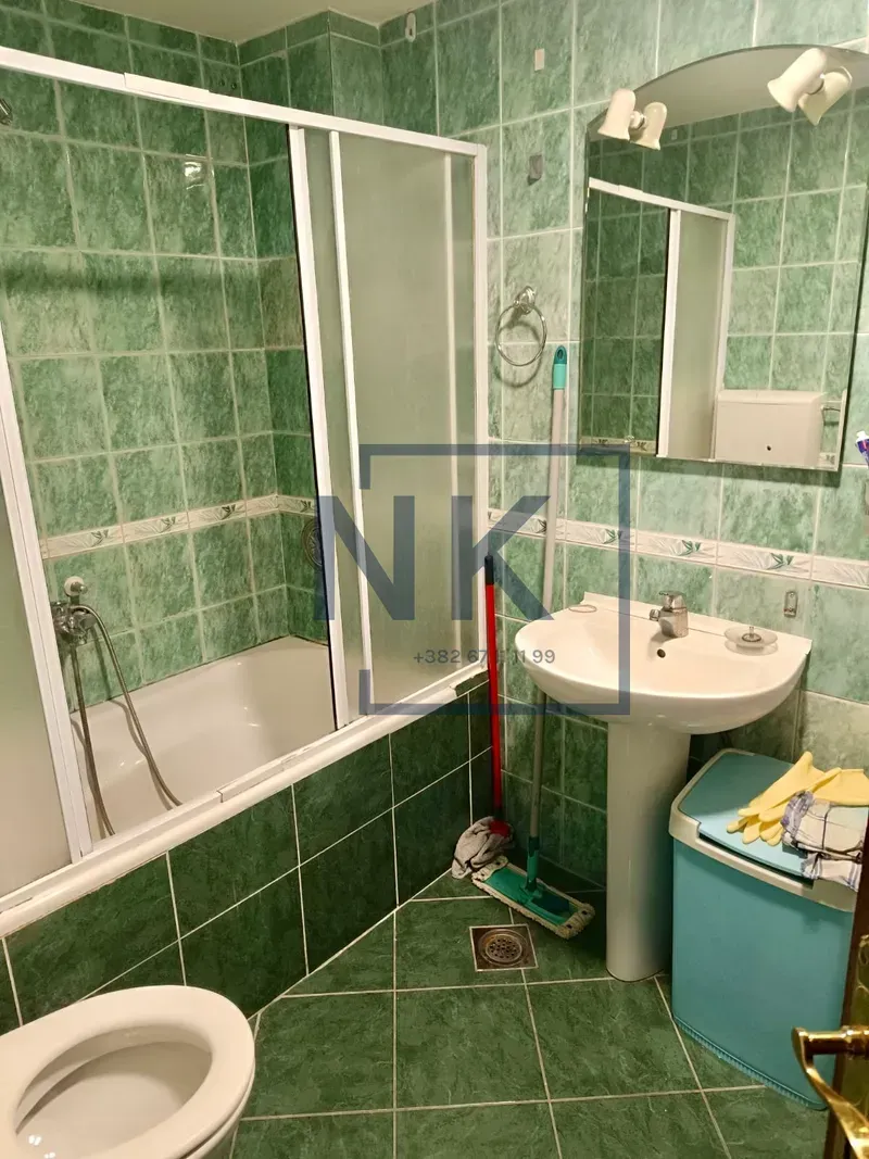 Bathroom tiled in green with a bathtub, washbasin, and toilet.